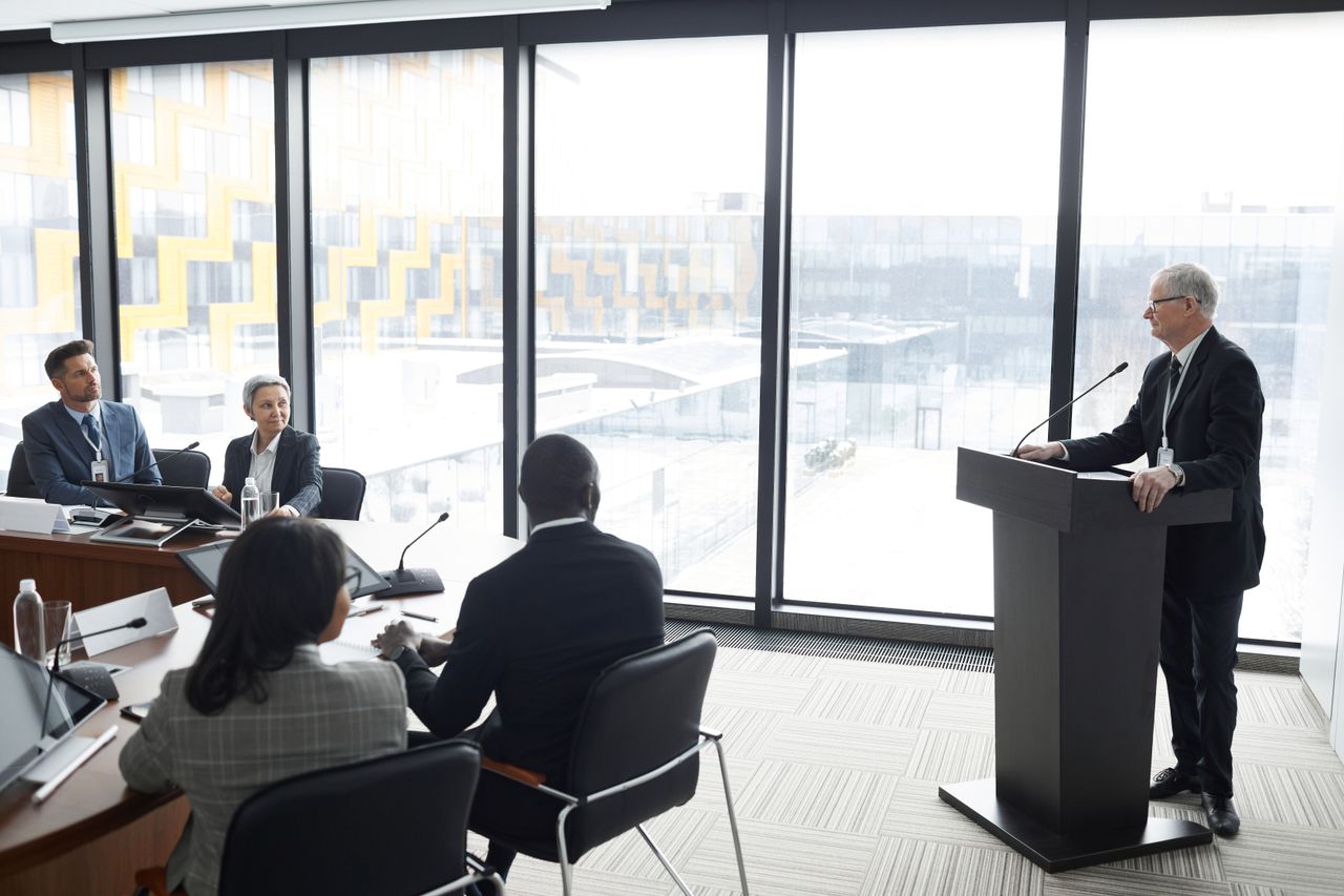 heros-img Corporate professionals engaged in a formal business meeting in a modern conference room setting.