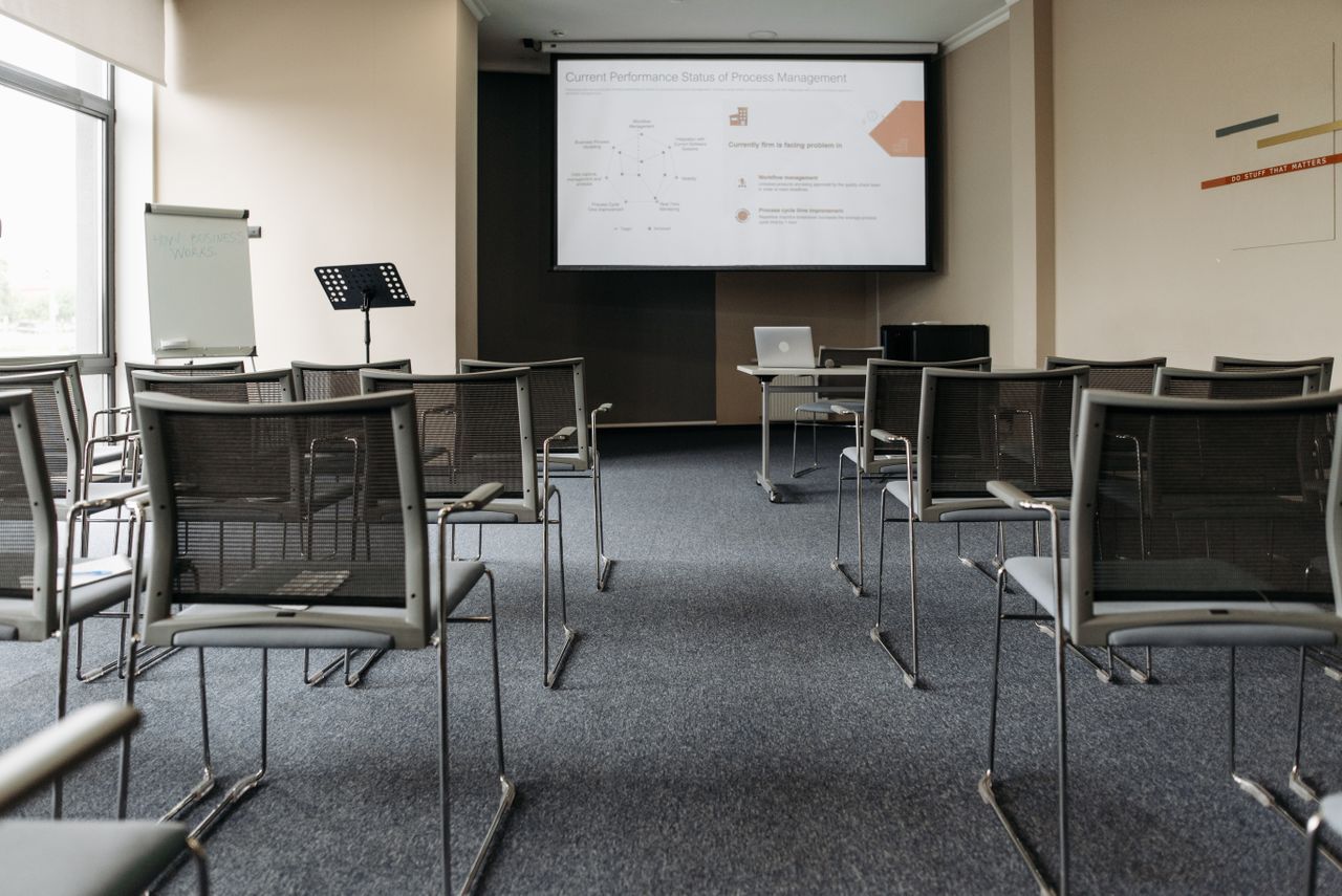 services-02 An empty conference room with chairs, a projector screen, and presentation setup.