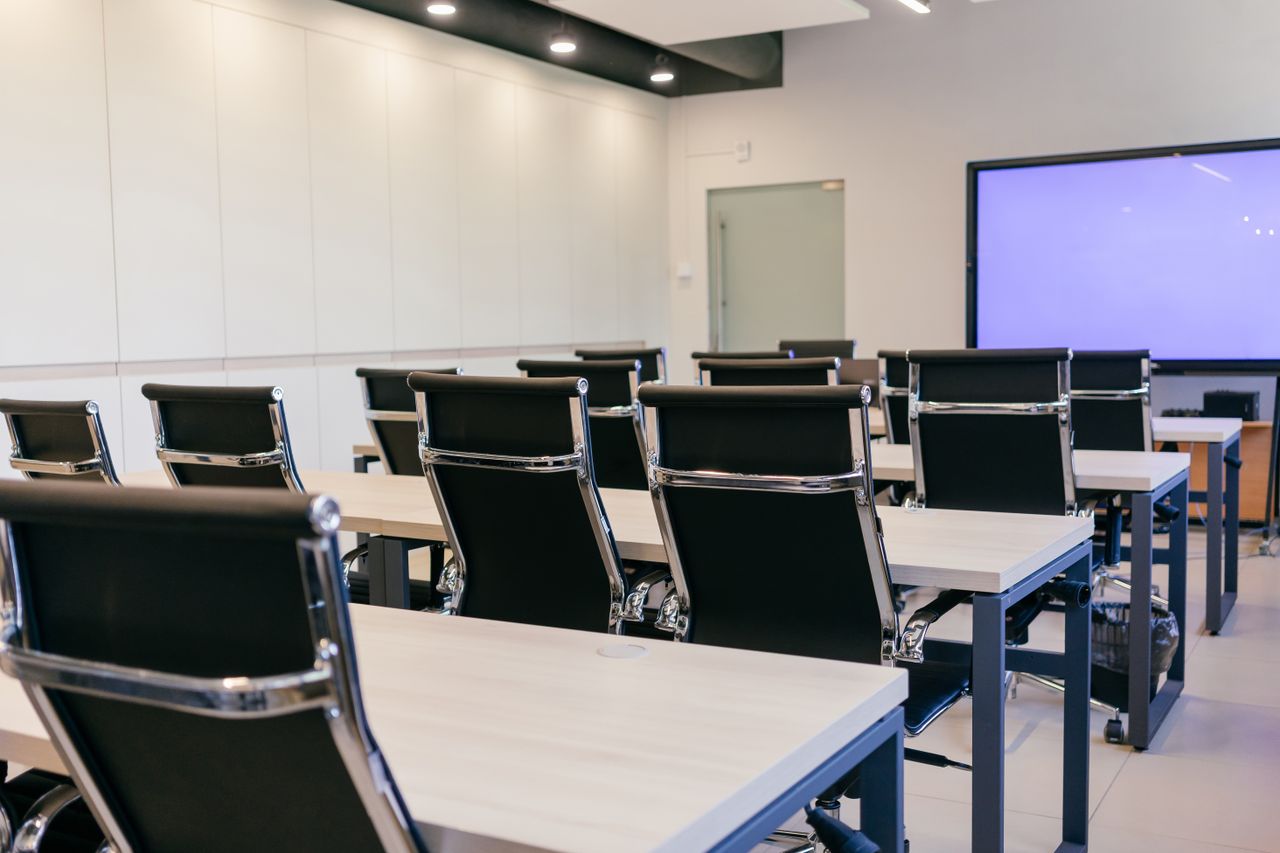 services-01 Spacious, modern conference room with black chairs and a projection screen.