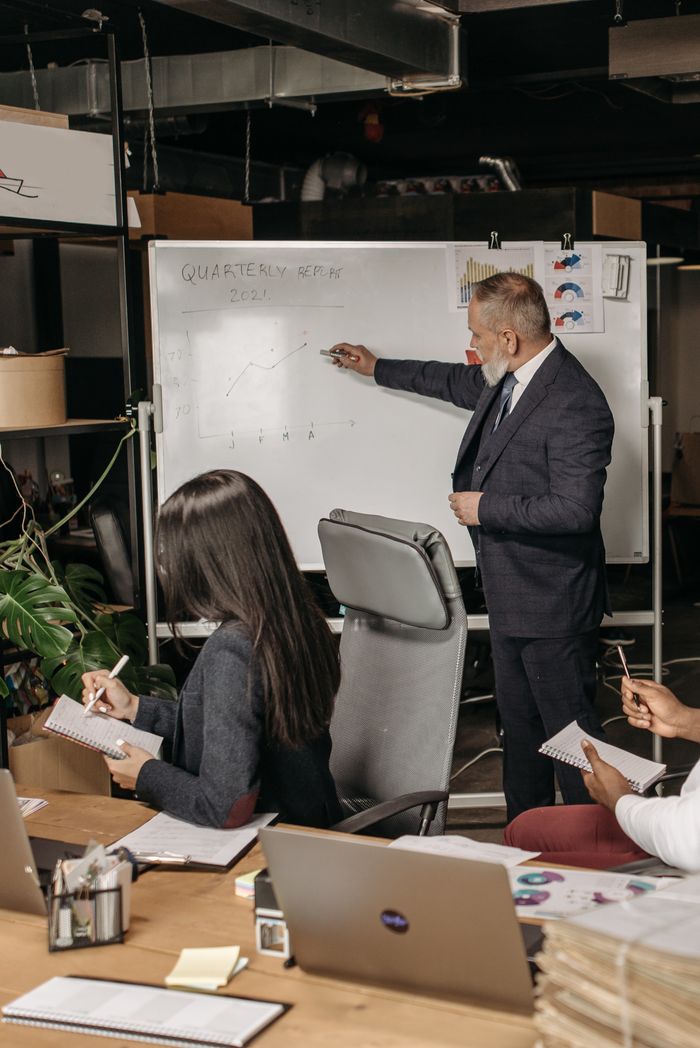 Crafting Captivating Headlines: Your awesome post title goes here Corporate meeting scene with a presenter analyzing quarterly returns on a whiteboard in an office setting.