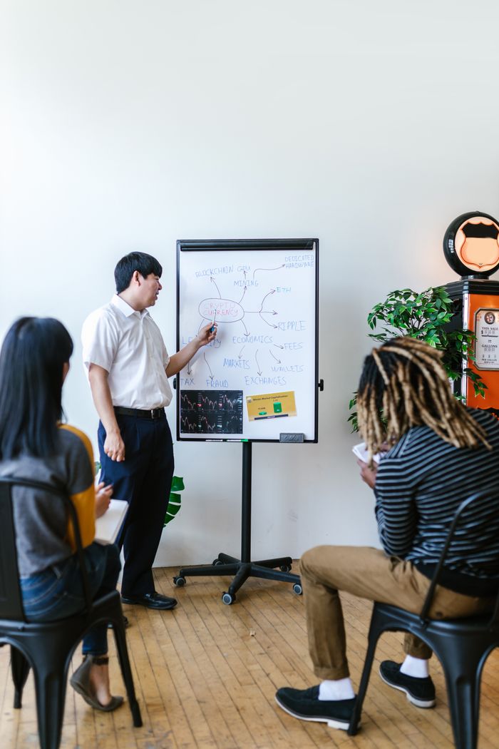 The Art of Drawing Readers In: Your attractive post title goes here Trainer giving a presentation on blockchain concepts to a diverse group in a modern office.